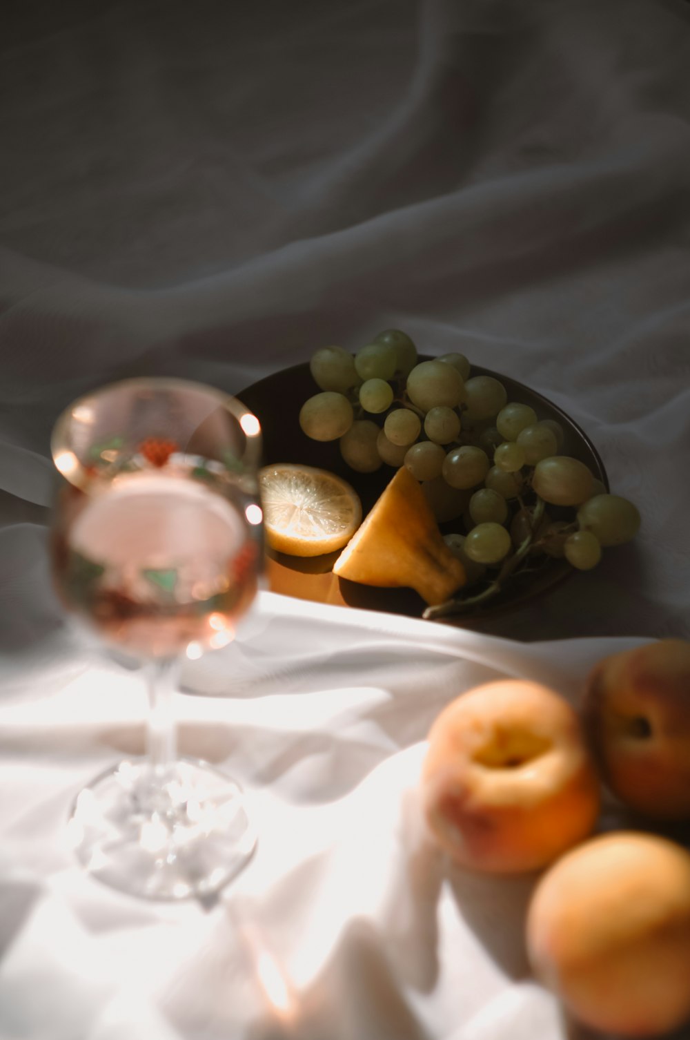 glass of cocktail beside plate of grapes and slice of cheese