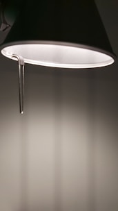 Close-up of a sleek gold-toned lamp casting gentle light on a white wall.