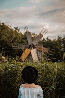 woman in white and black off-shoulder top standing near windmill during daytime