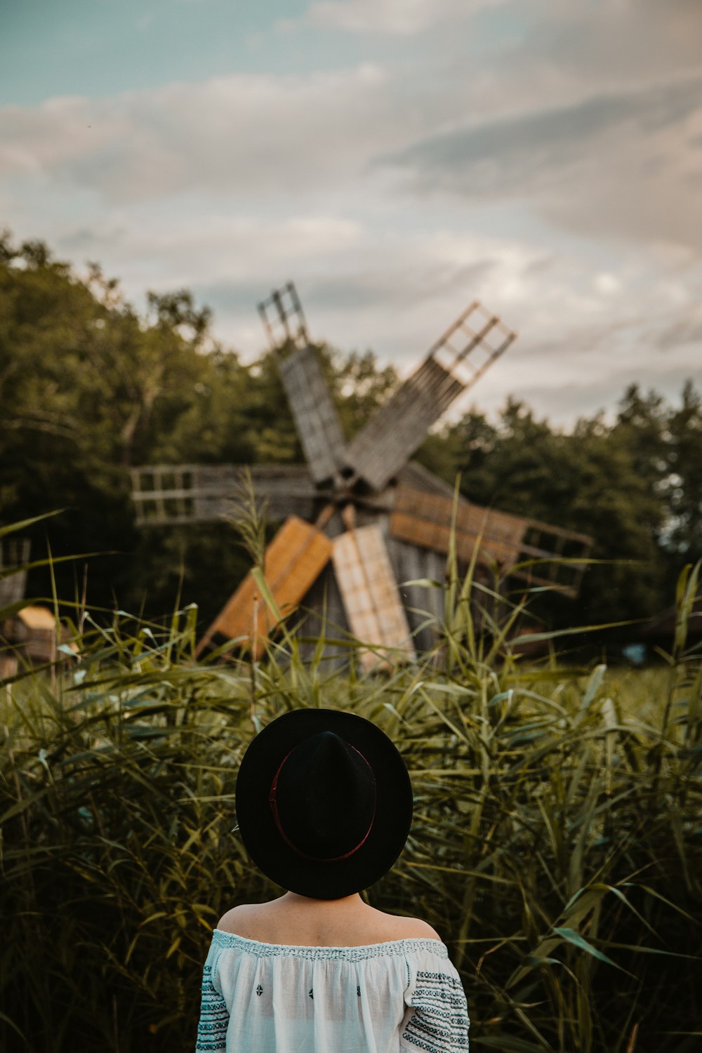 woman in white and black off-shoulder top standing near windmill during daytime