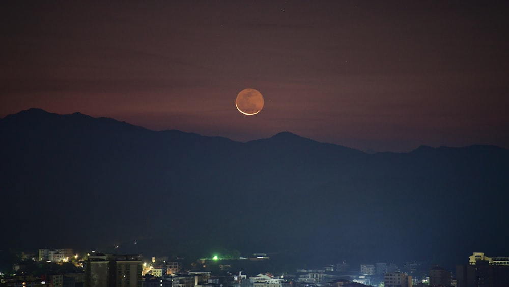 uma lua cheia é vista sobre uma cidade à noite