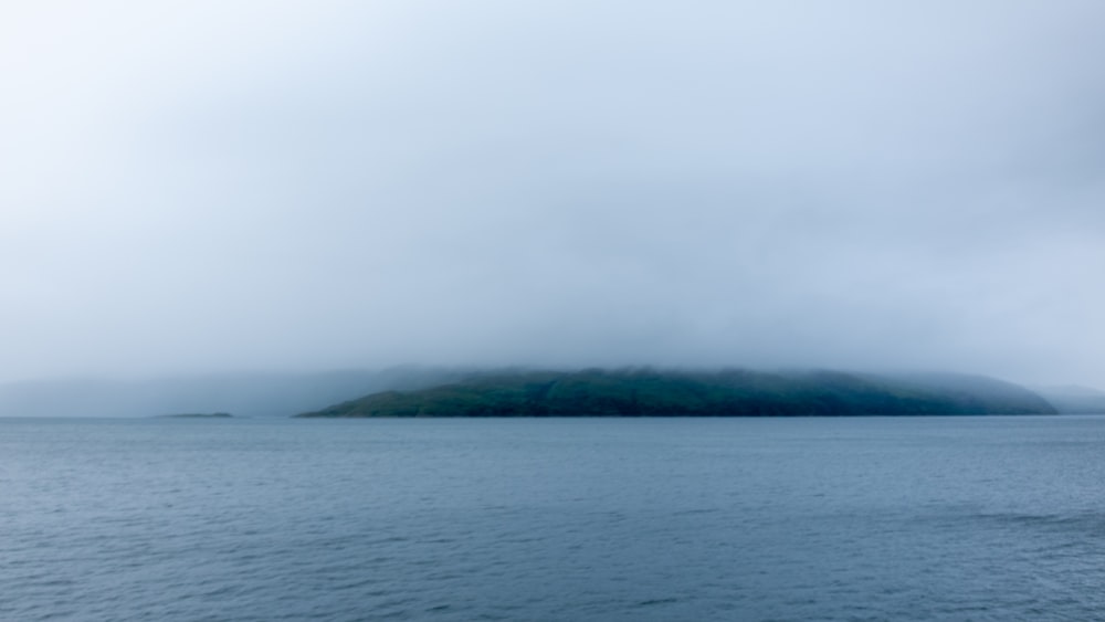 calm body of water near mountain during daytime