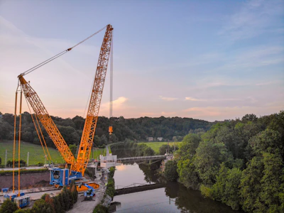 A sturdy crane lifting materials with Bali's lush landscape in the background.