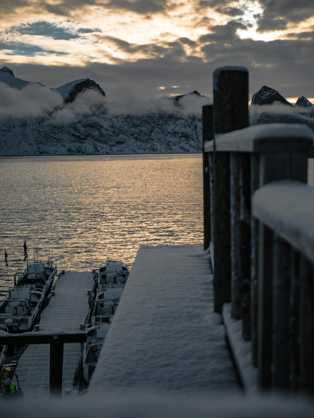 a boat dock with snow on the ground and mountains in the background