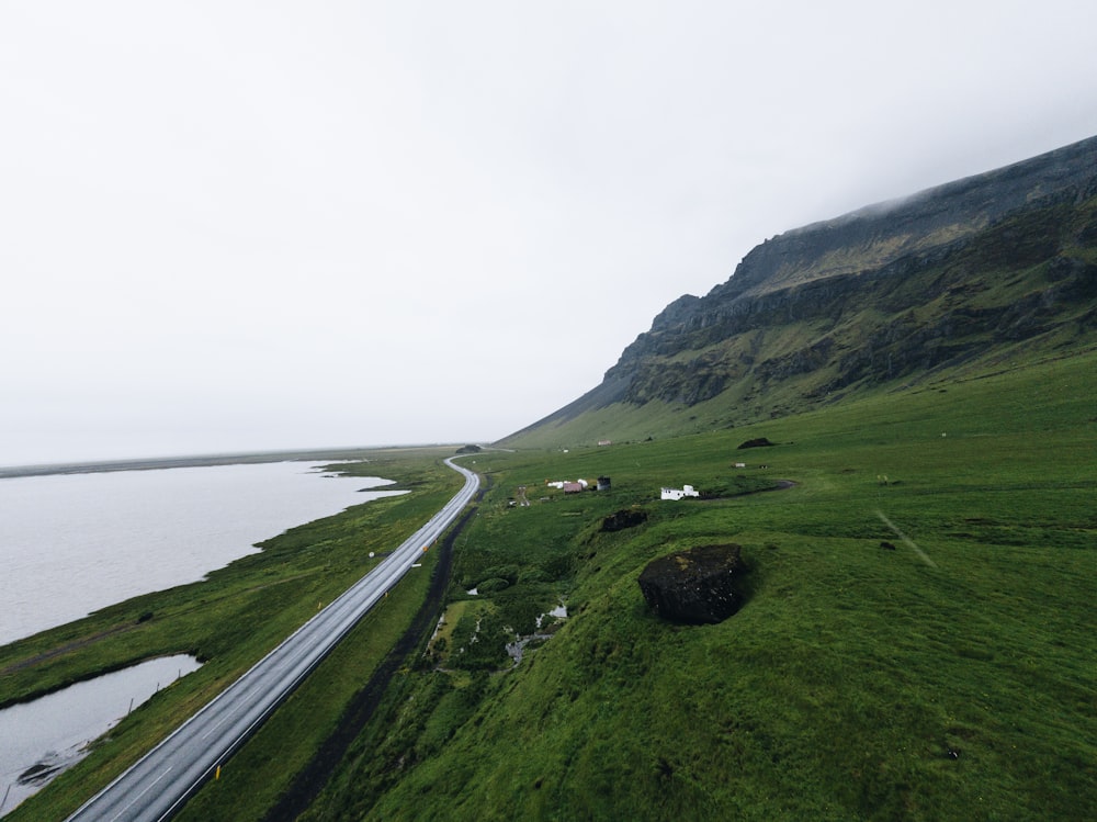 estrada de concreto cinza perto do campo verde vendo a montanha e o mar