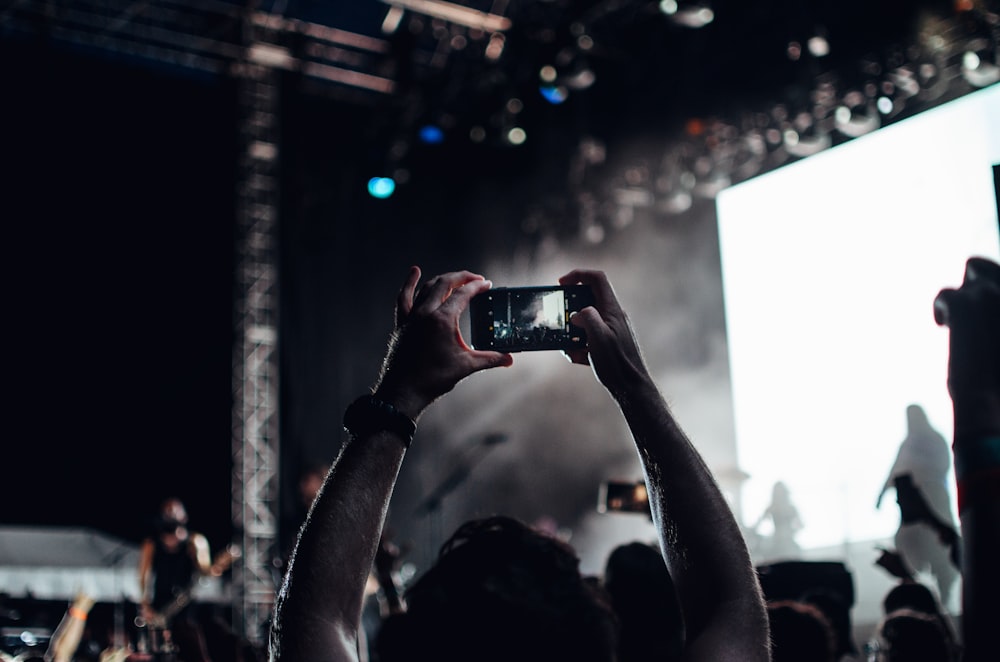 person taking photo of people performing on stage