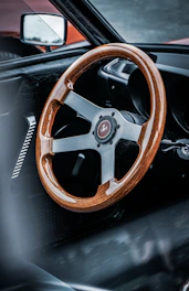 A variety of steering wheels displayed on a wooden table.