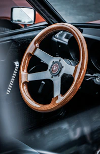 A variety of steering wheels displayed on a wooden table.