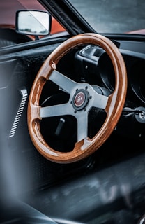 A collection of various personalized steering wheels arranged on a wooden table.