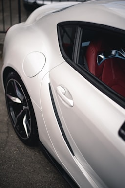 A close-up of a sleek, black car shirt with red and white details displayed on a wooden table beside a laptop.