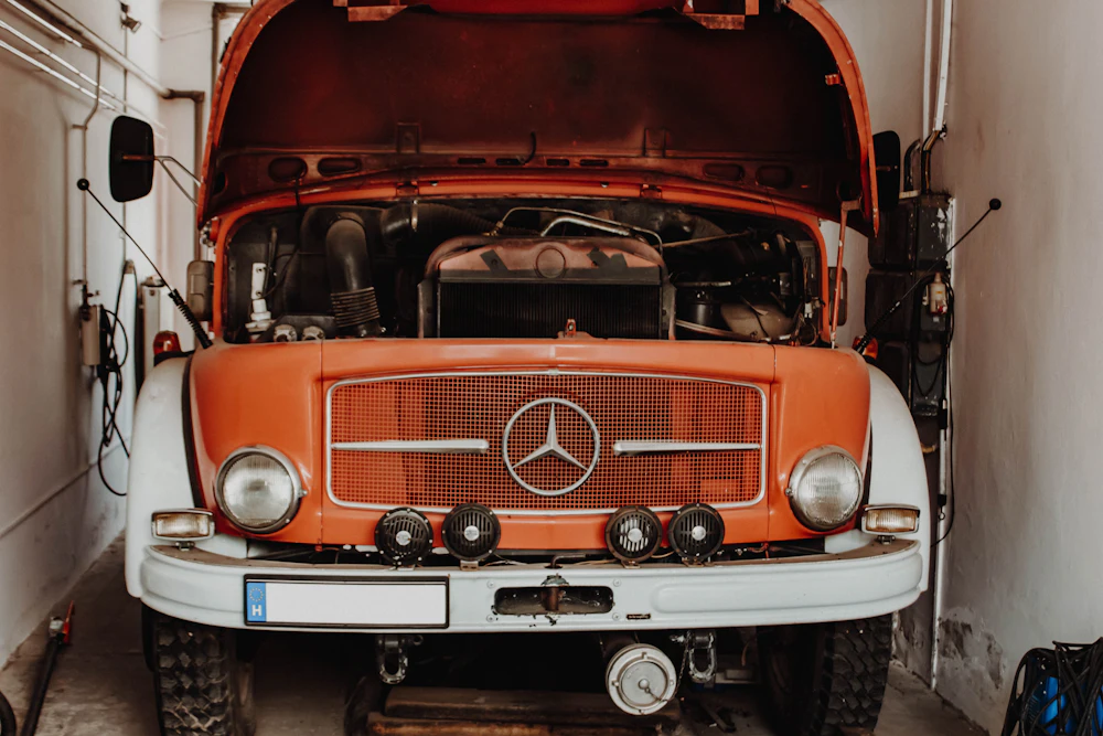 A classic Mercedes-Benz with its hood raised inside a service bay