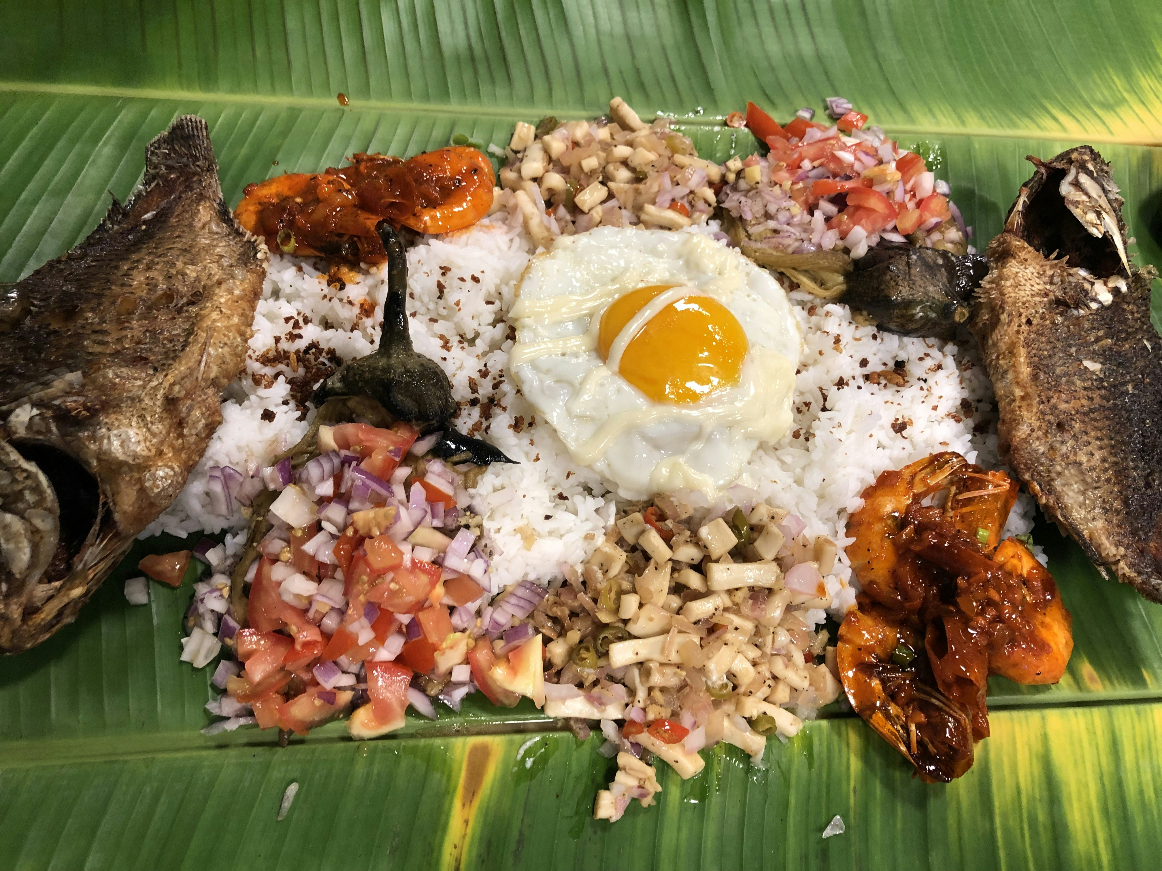 Traditional Filipino pork dish with crispy skin served on banana leaf with steamed rice and vegetables