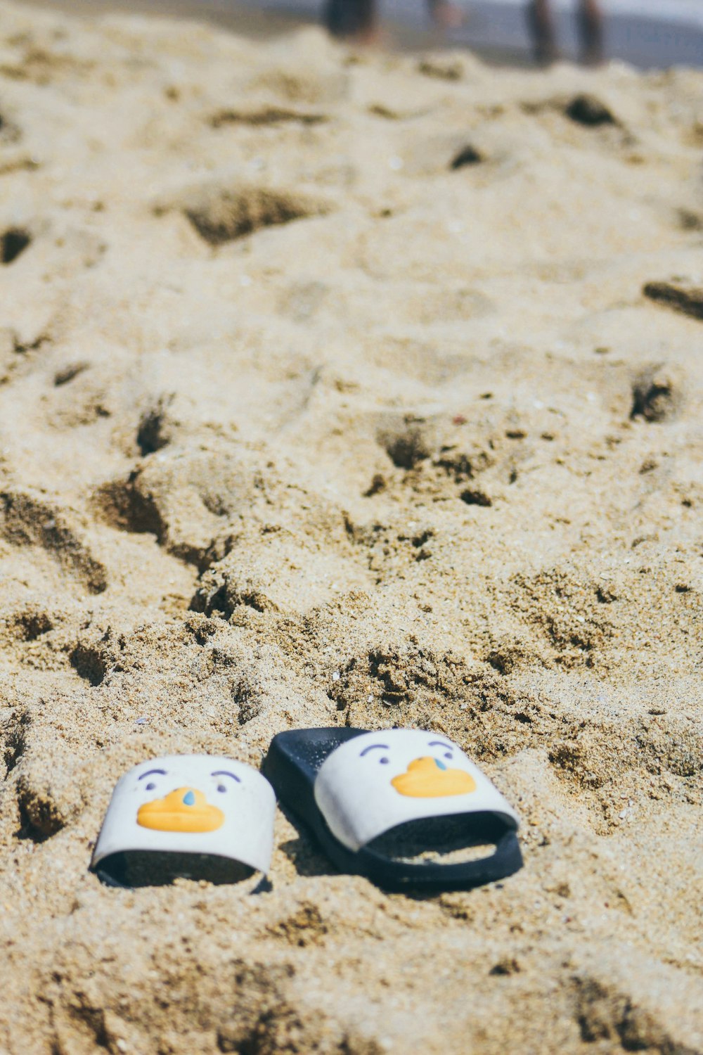 pair of white-and-black slide sandals on white sand