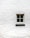 A single window with four panes is positioned in the center of a white brick wall. The wall's texture is rough, and the window frame appears to be made of wood, painted in a light color.