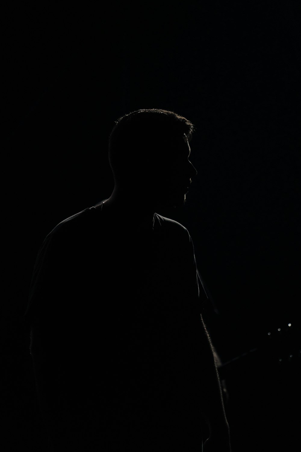 a man standing in the dark with a guitar