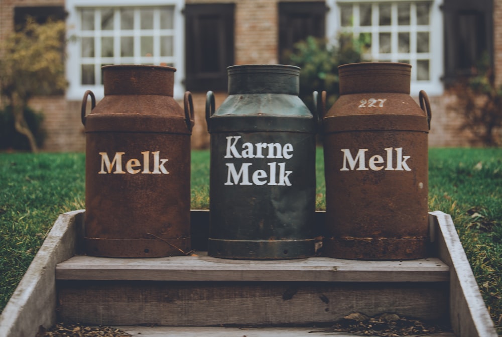 three brown and black milk urns