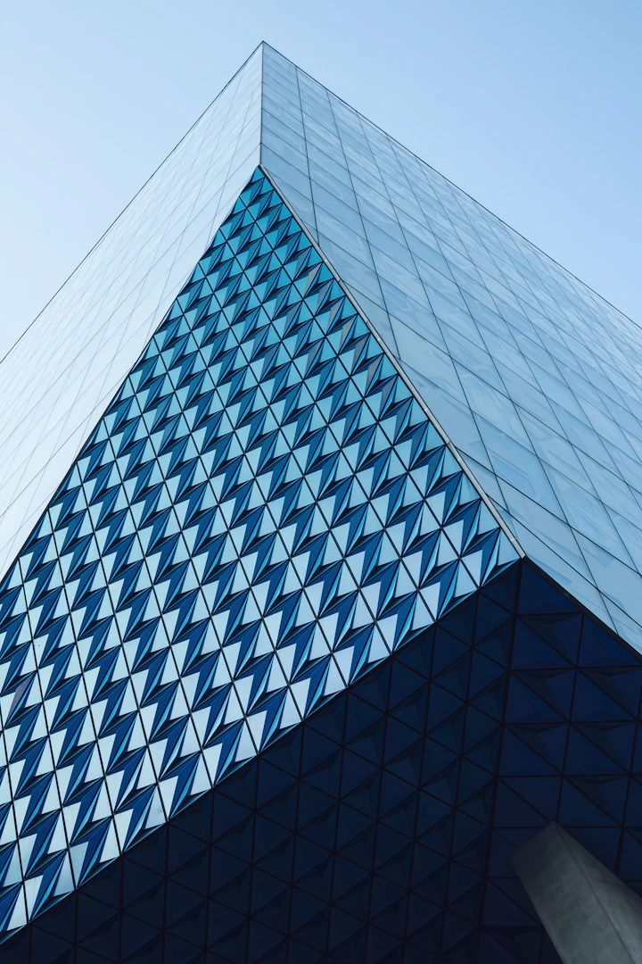Triangular glass panels on a blue architectural facade