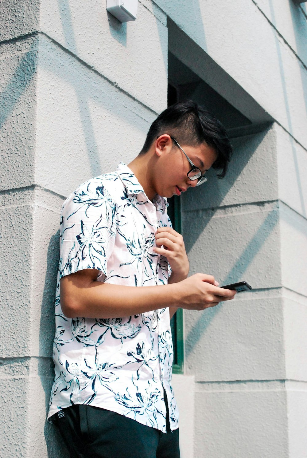 man leaning on wall holding smartphone