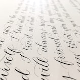 Elegant black cursive handwriting is beautifully arranged on a light-colored paper background, showcasing smooth curves and flowing script.
