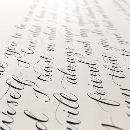 Close-up of a skilled hand writing elegant cursive on textured paper.