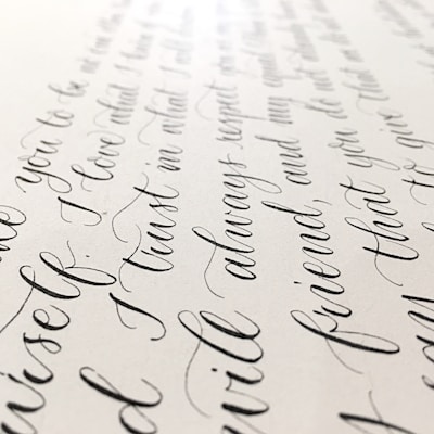 Elegant black cursive handwriting is beautifully arranged on a light-colored paper background, showcasing smooth curves and flowing script.