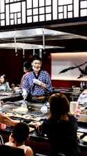 A chef demonstrating cooking techniques to an engaged audience in a lively workshop setting.
