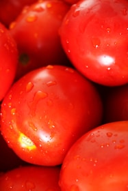 Close-up of ripe tomatoes glistening with morning dew on a market stand.