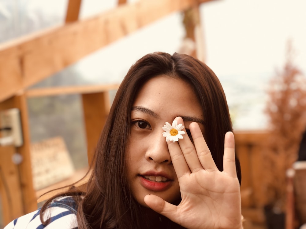 woman in white and blue striped shirt holding white-petaled flower