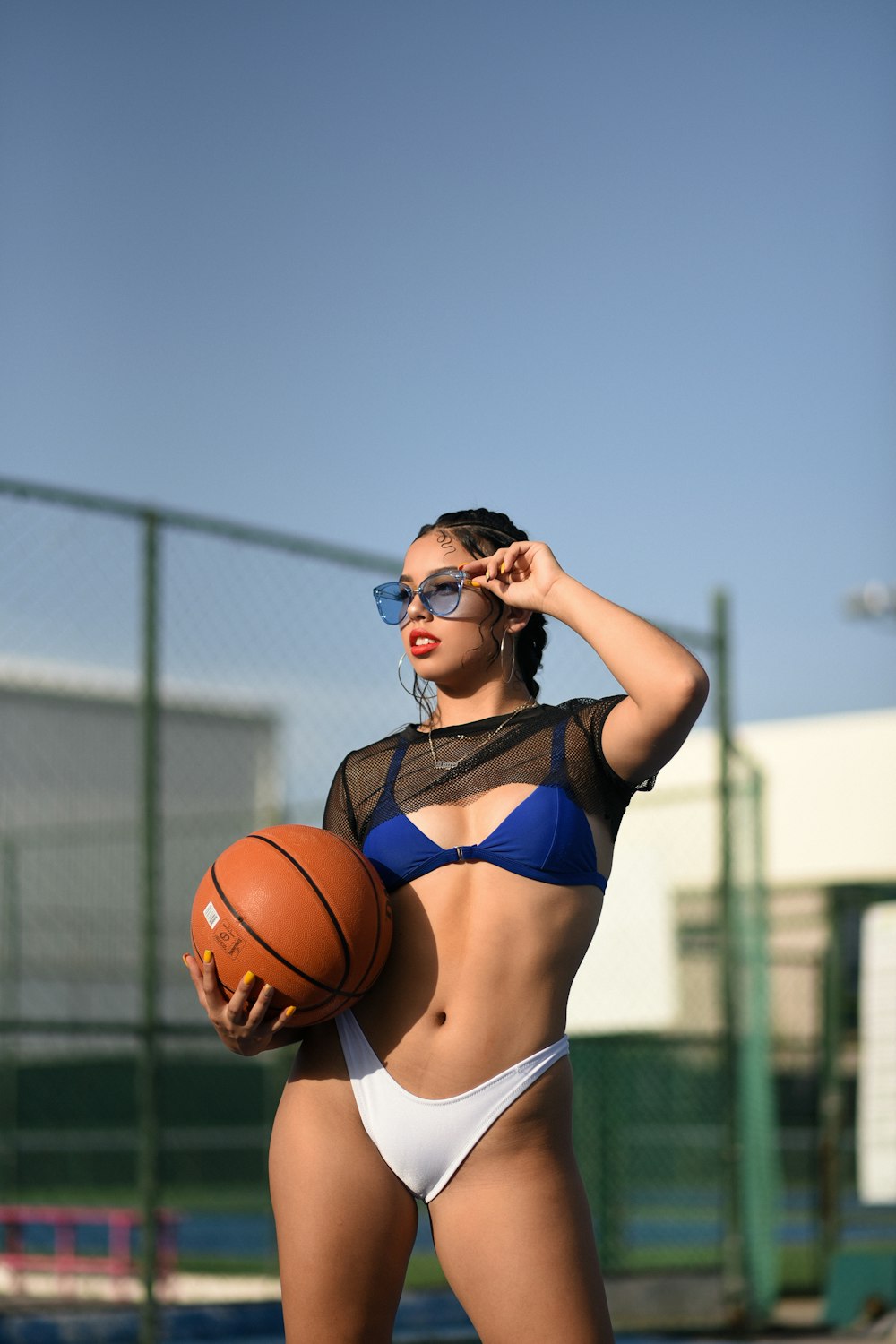 Frau in weißem und blauem BH und Höschen hält Basketball