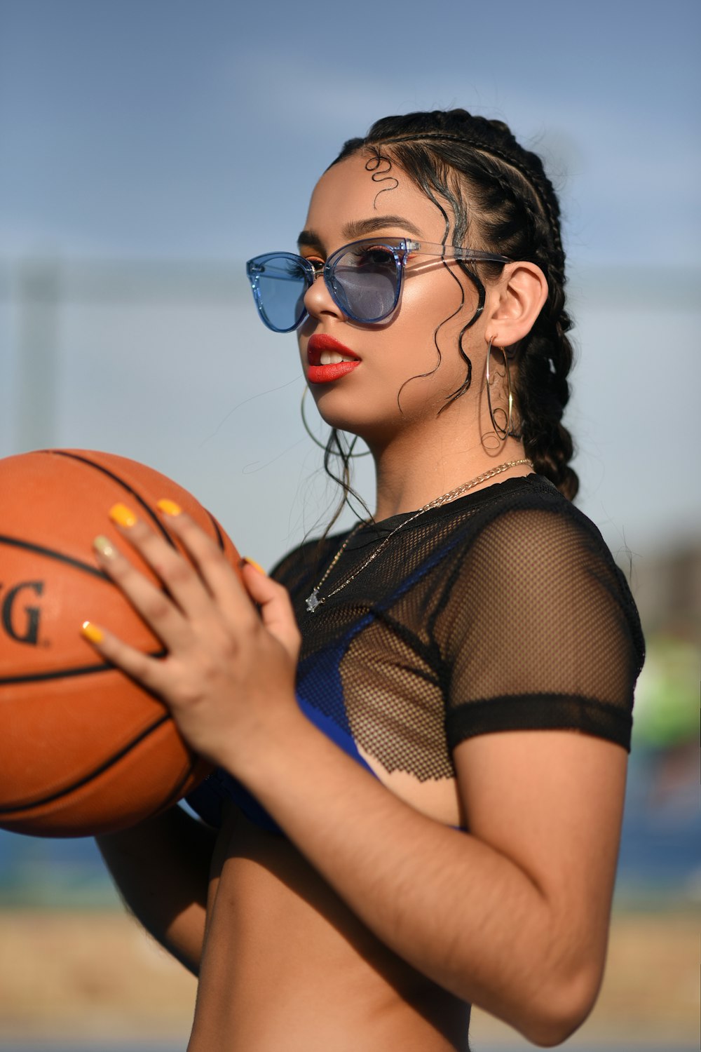 Mujer en top corto de malla negra sosteniendo baloncesto