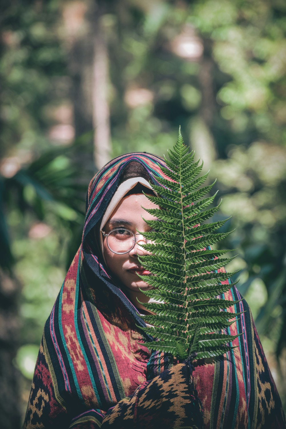 woman covering her face with Boston fern leaf