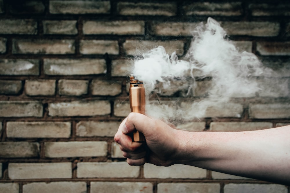 person holding gold-colored smoking pipe