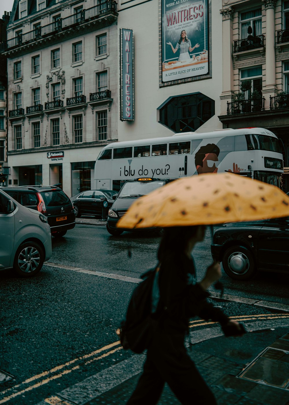 a woman walking across a street holding an umbrella