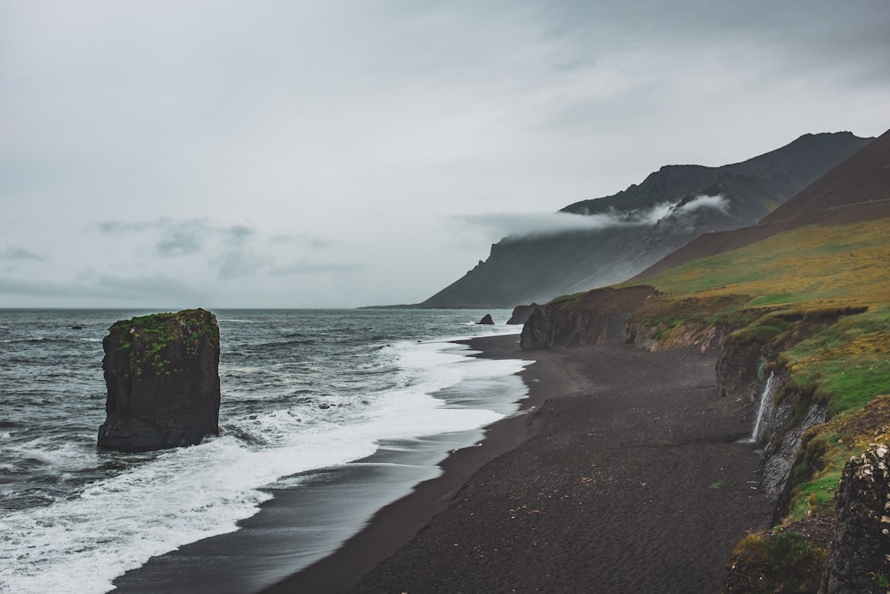 brown rock on seashore across horizon during cloudy daytime