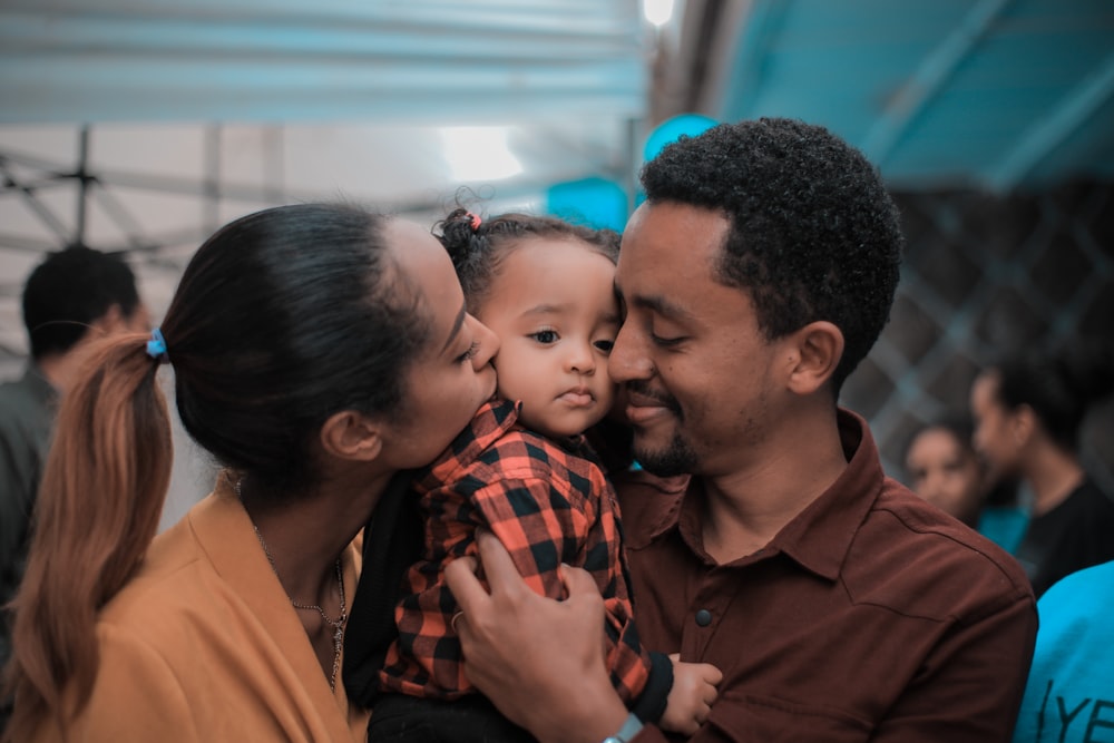 two person holding a kid close-up photography