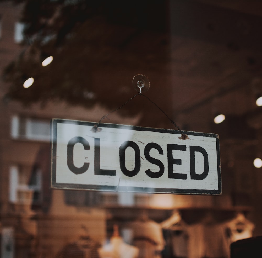 black and white Closed sign plate on glass panel