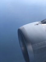 A close-up view of an aircraft engine against a backdrop of a clear sky. The metallic surface of the engine is sleek and smooth, reflecting light subtly.