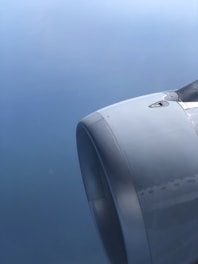 A close-up view of an aircraft engine against a backdrop of a clear sky. The metallic surface of the engine is sleek and smooth, reflecting light subtly.