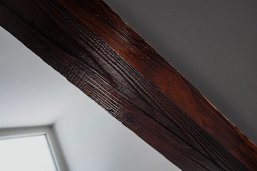 Close-up of a technician inspecting wooden beams for termites in a bright, clean home.