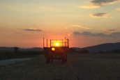 A Terratrek camper silhouetted against a sunset over rolling hills.