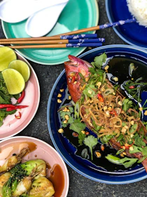 Close-up of a colorful Asian fusion dish with fresh herbs and vibrant spices on a rustic plate.