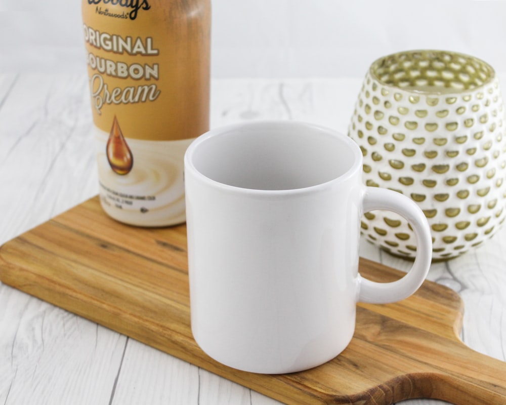 white mug near brown labeled can and vase close-up photography