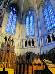 Majestic stained glass window casting colorful light inside a grand church interior.