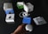 A collection of Google products and their packaging are spread out on a dark surface. Items include boxes for Google Home Mini, Chromecast, and a smart plug. Next to the boxes, an unboxed Google Home Mini, power cable, and several information cards in different colors are visible. A person's hand is reaching towards the Google Home Mini.