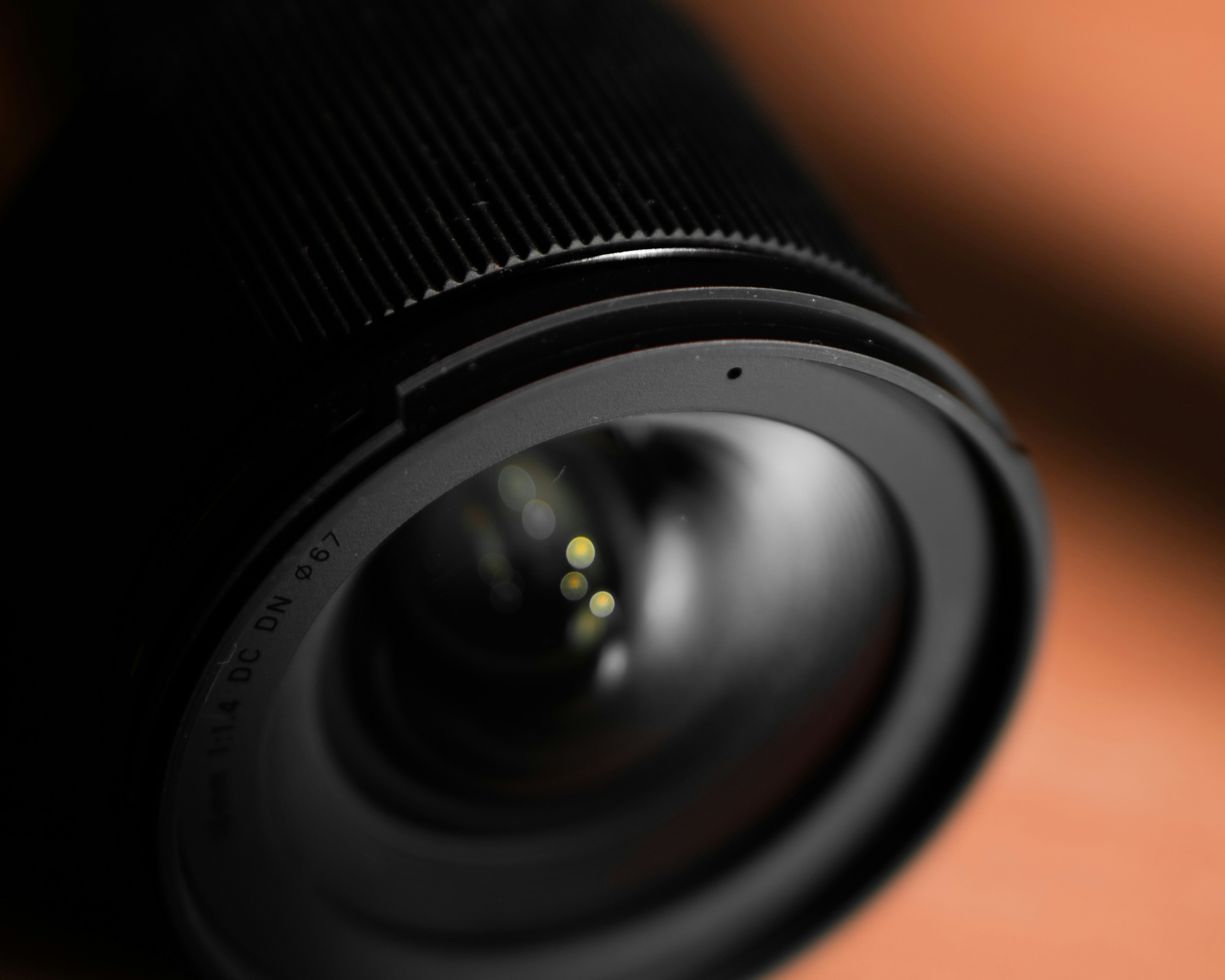 Film camera close-up with dramatic side lighting, deep shadows, cinematic orange bokeh background