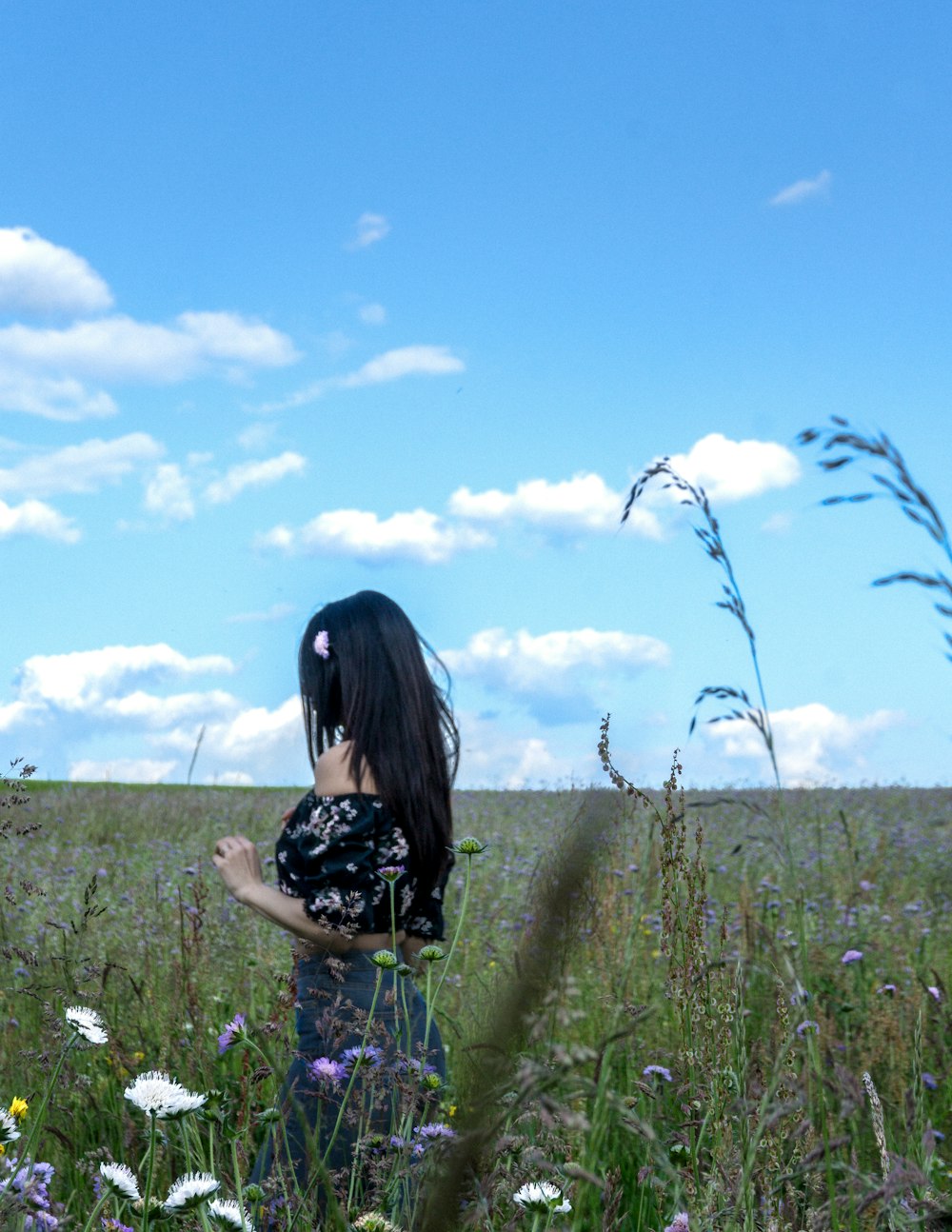 Mulher que caminha na grama verde sob o céu azul
