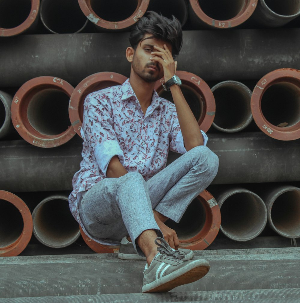 man sitting near pile of pipes