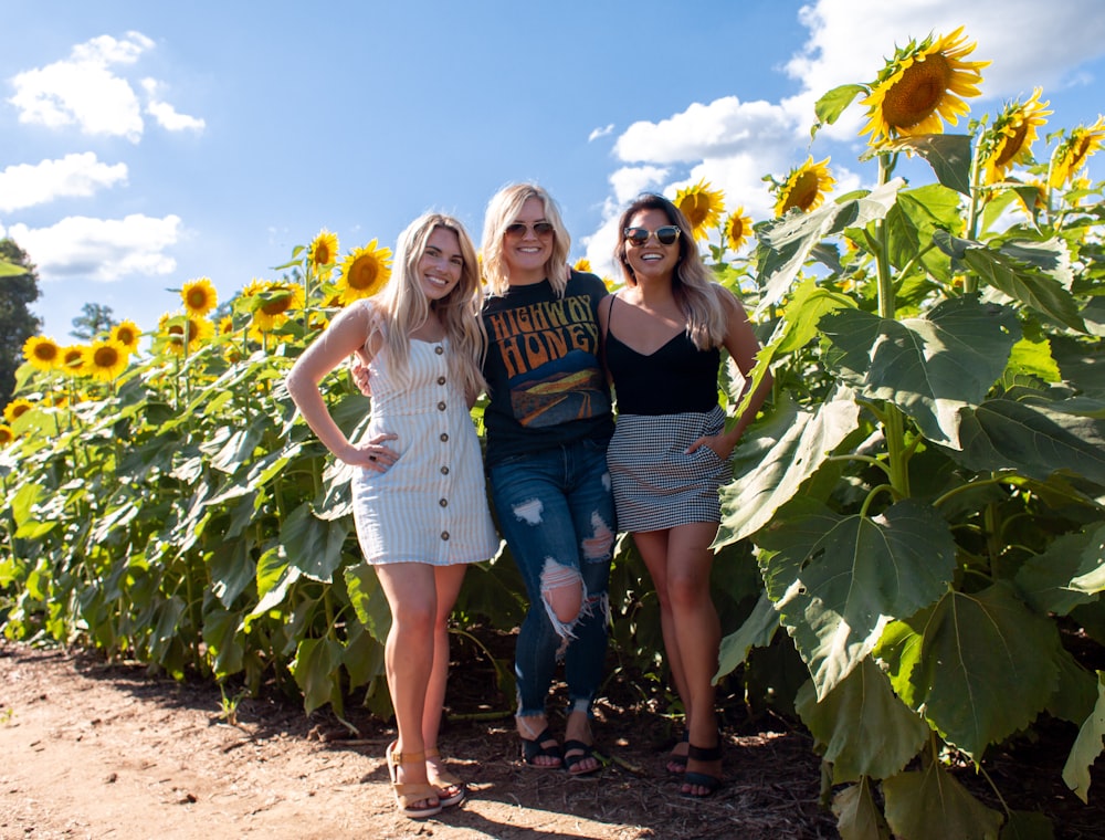three women standing at the sunflower farm during daytime