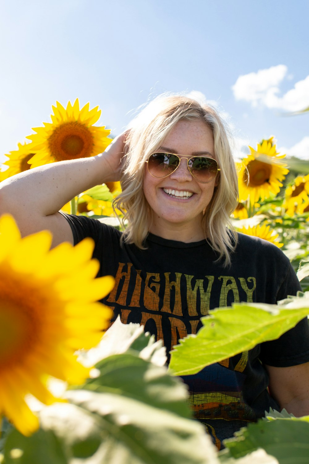 smiling woman standing near sunflower field
