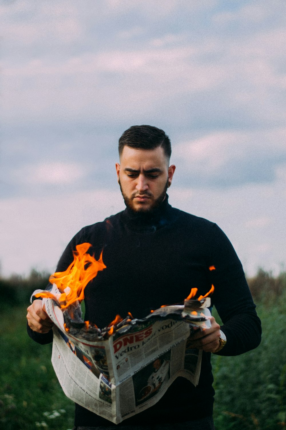 unknown person holding lit newspaper